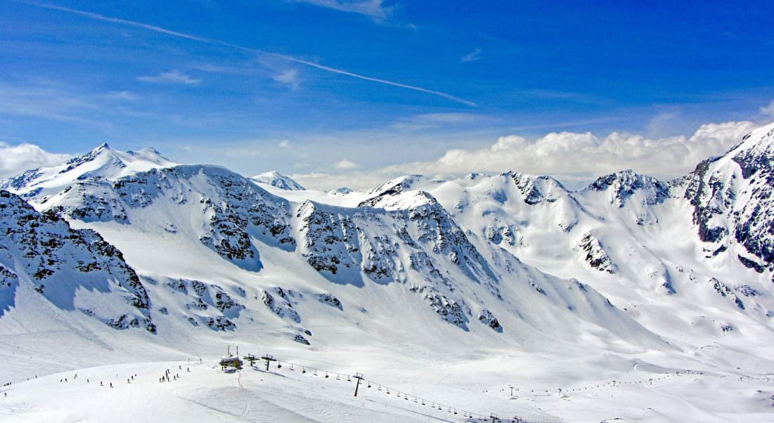 A beautiful view of the mountains with snow all over them and a ski lift below.