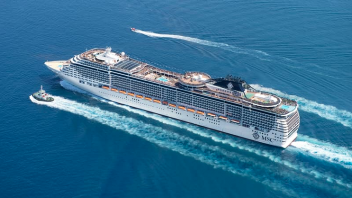 An aerial photo of a cruise ship with some smaller boats on either side.