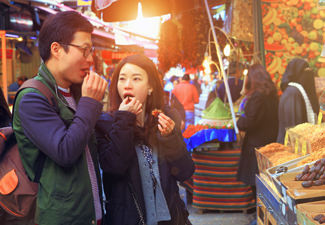 young-couple-trying-food-at-city-market