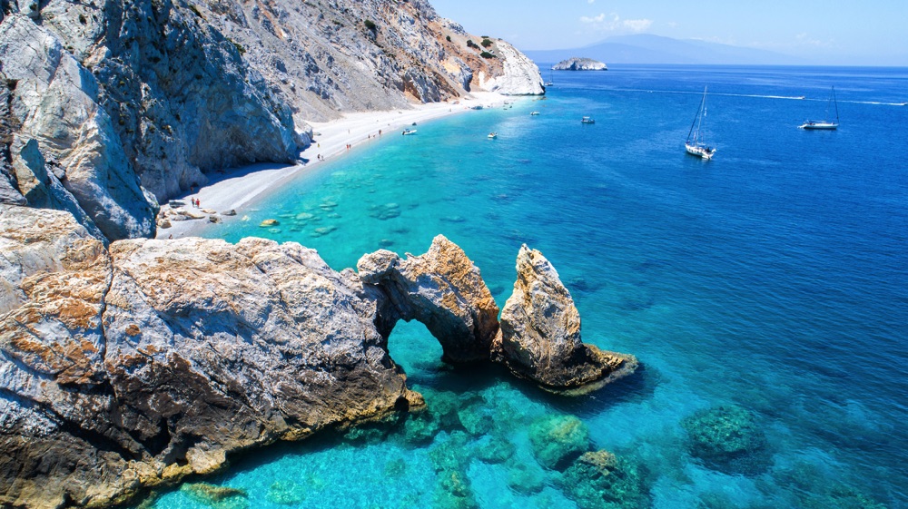 The tall cliffs and sky-blue water in Lalaria, Skiathos, one of the nicest beaches in Greece