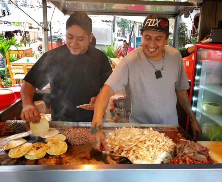 Two guys working cooking street food in a market in mexico