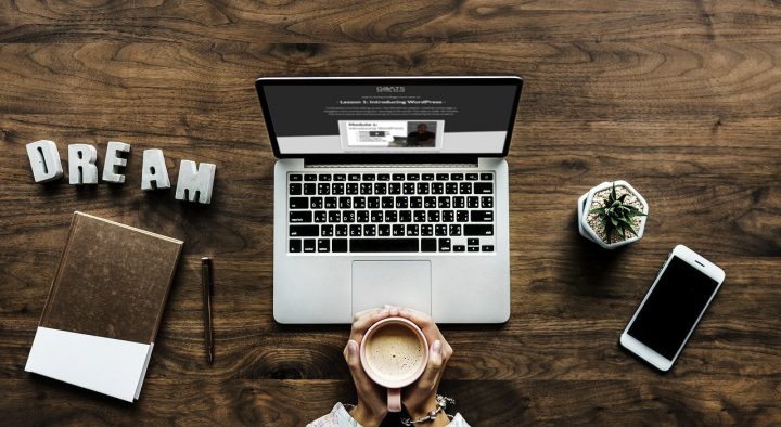 A desktop computer with someone drinking a coffee (shot from above) to demonstrate the work of freelance writers