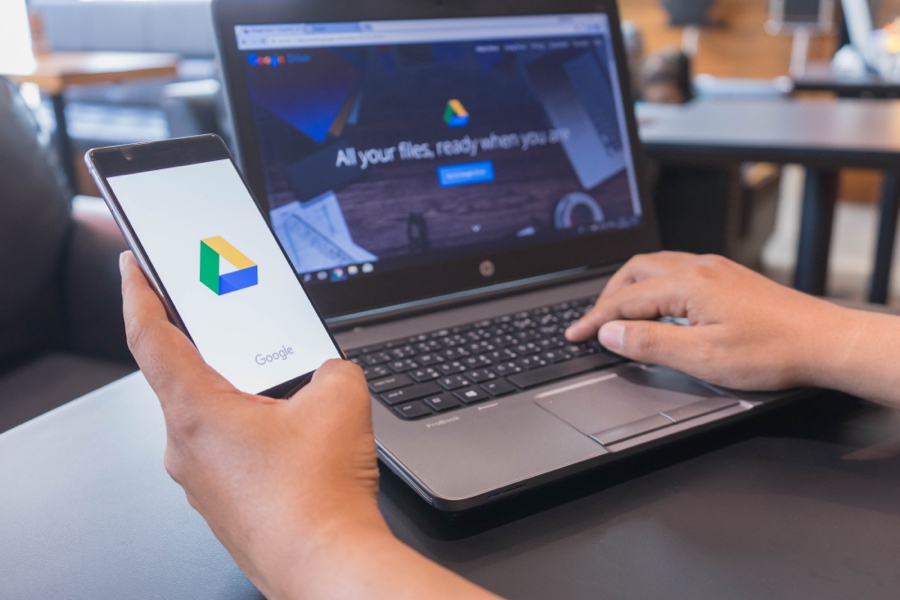 Man on computer with google products open on his phone