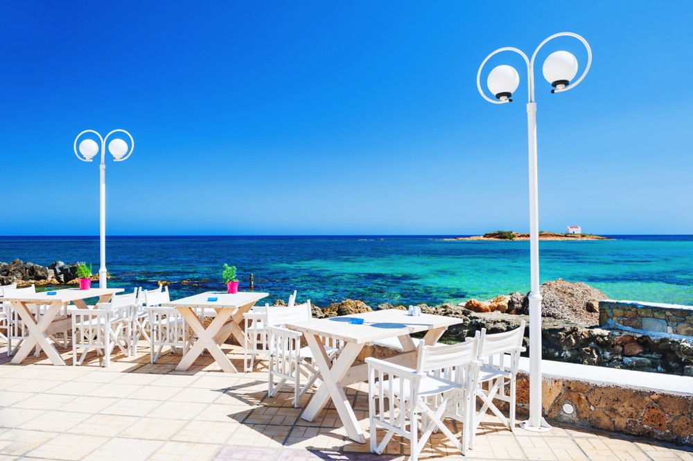 Seaside deck with tables and chairs in Malia, one of the most fun places to visit in Crete