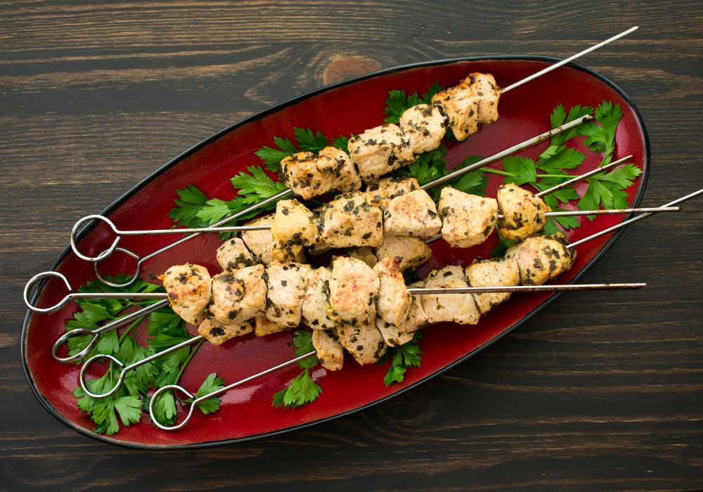 A platter of pork souvlaki on a wooden table.