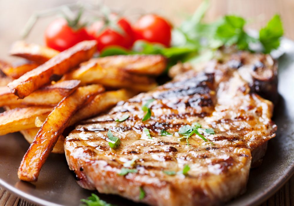 Grilled mongolian pork chop with french fries on a platter.