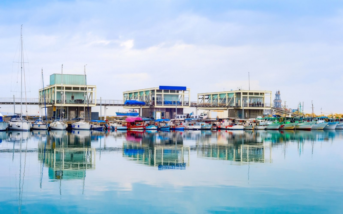 Limassol marina with yachts and fishing boats moored by pier with restaurants in Limassol, Cyprus.