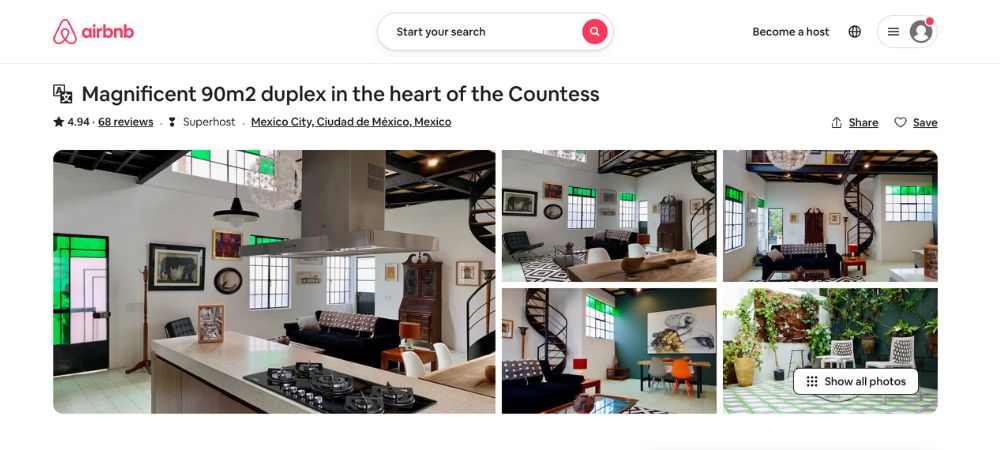 A huge open-area apartment with large windows on both floors and a kitchen with a center island for cooking and for food preparation, with comfortable chairs and a dining table.