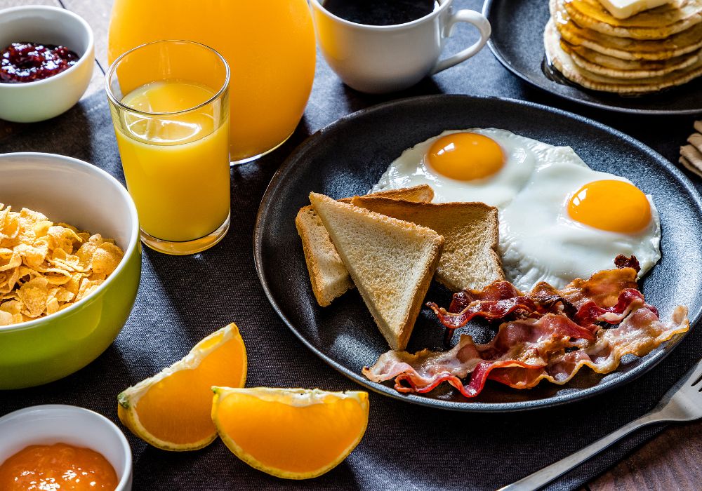 High angle view of an American breakfast made with fried eggs, toasted brea, bacon and pancakes.