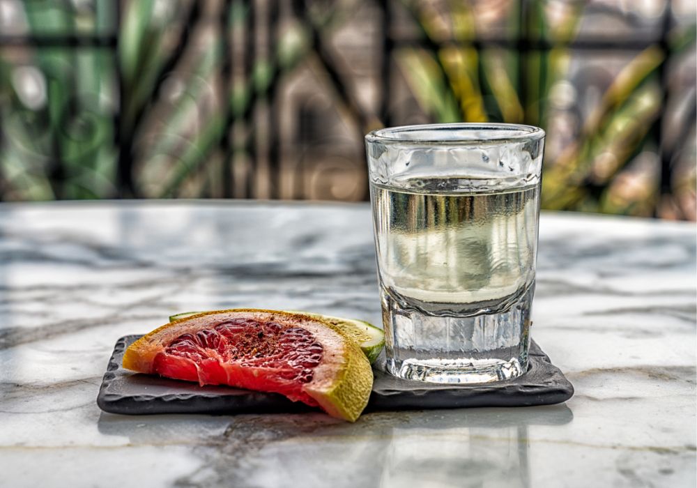 Shot of mezcal on a table with a blurry background.