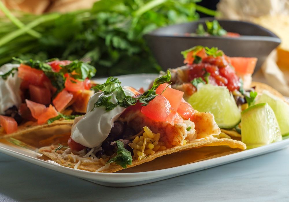 Mexican chicken tostada flat tacos with rice black beans and sour cream.