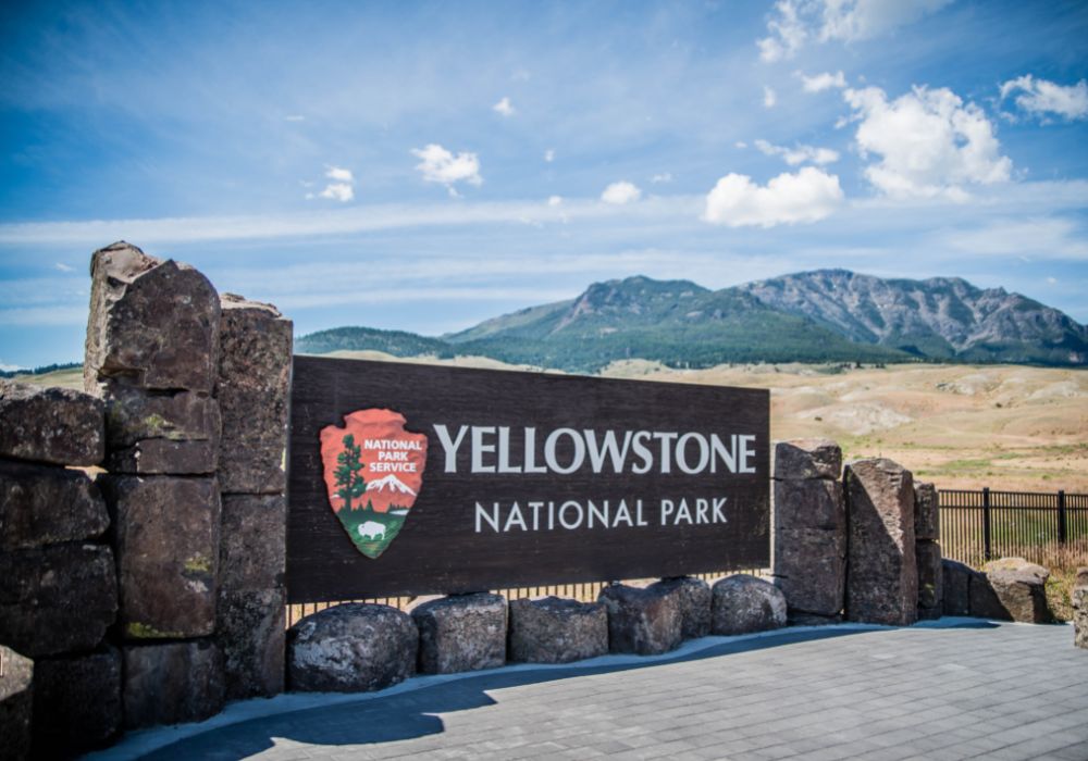 Yellowstone National Park sign with a desert and mountain in the background.