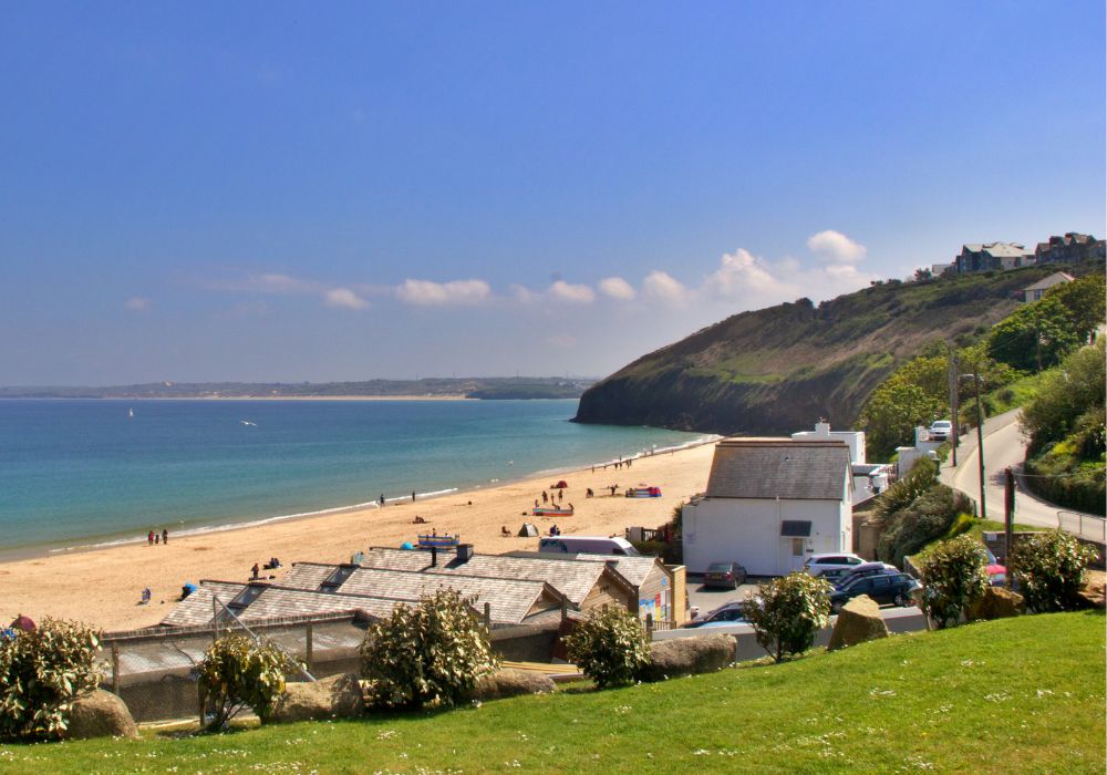 beach at penzance cornwall with houses and a cliff