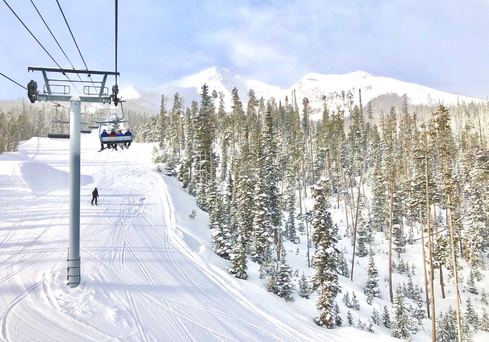 Tourists are skiing in Big Sky, Montana, with a huge mountain and great views.