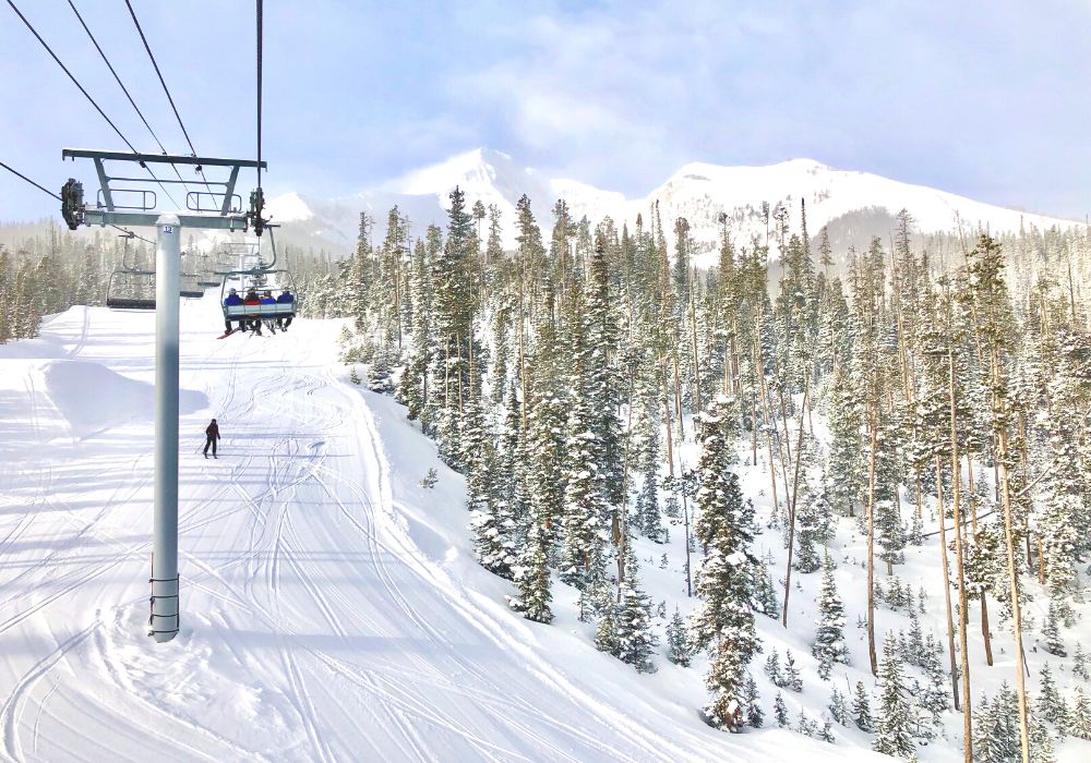 Tourists are skiing in Big Sky, Montana, with a huge mountain and great views.