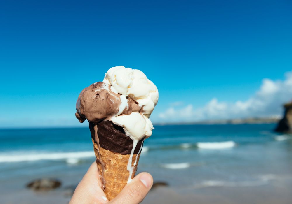 Multi-flavored melting-ice cream cone over looking the main town beach in Newquay, Cornwall on a sunny day.