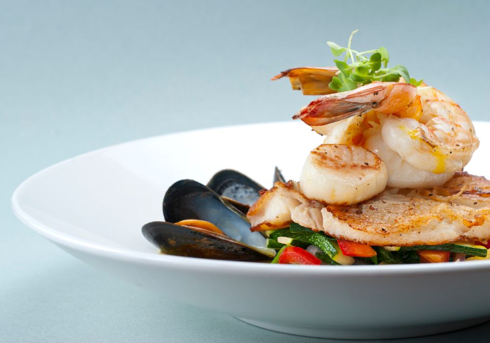 A seafood medley of shrimp, scallops, mussels, and fresh fish over a bed of vegetables.