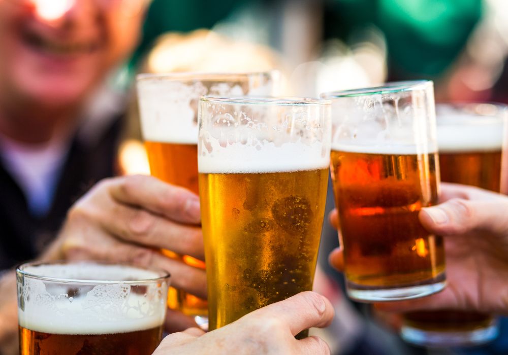A close-up color image depicting a group of people celebrating with a toast while cheering their glasses.