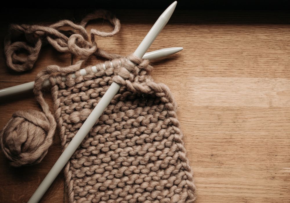 Knitting needles and yarn on wooden surface.