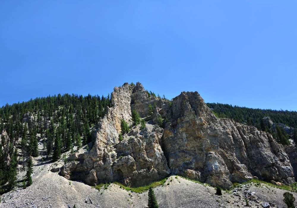 The rugged crevices and ridges rise out of the Gallatin Mountain Range in Montana with a sunny blue sky above.