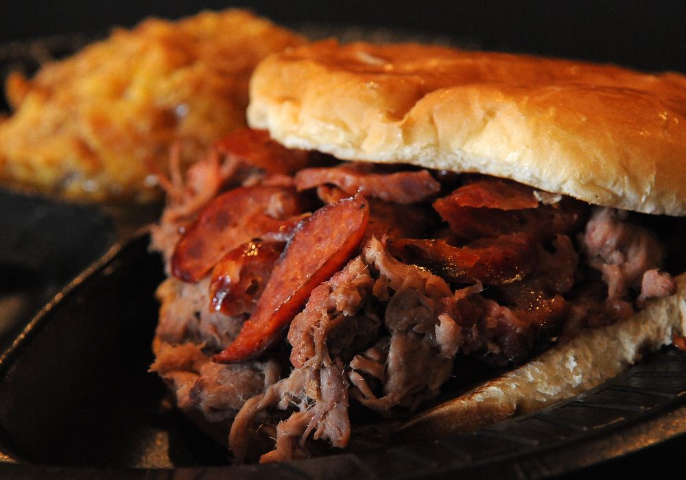 The brisket sandwich is topped with a pork hot link and served with peach cobbler.