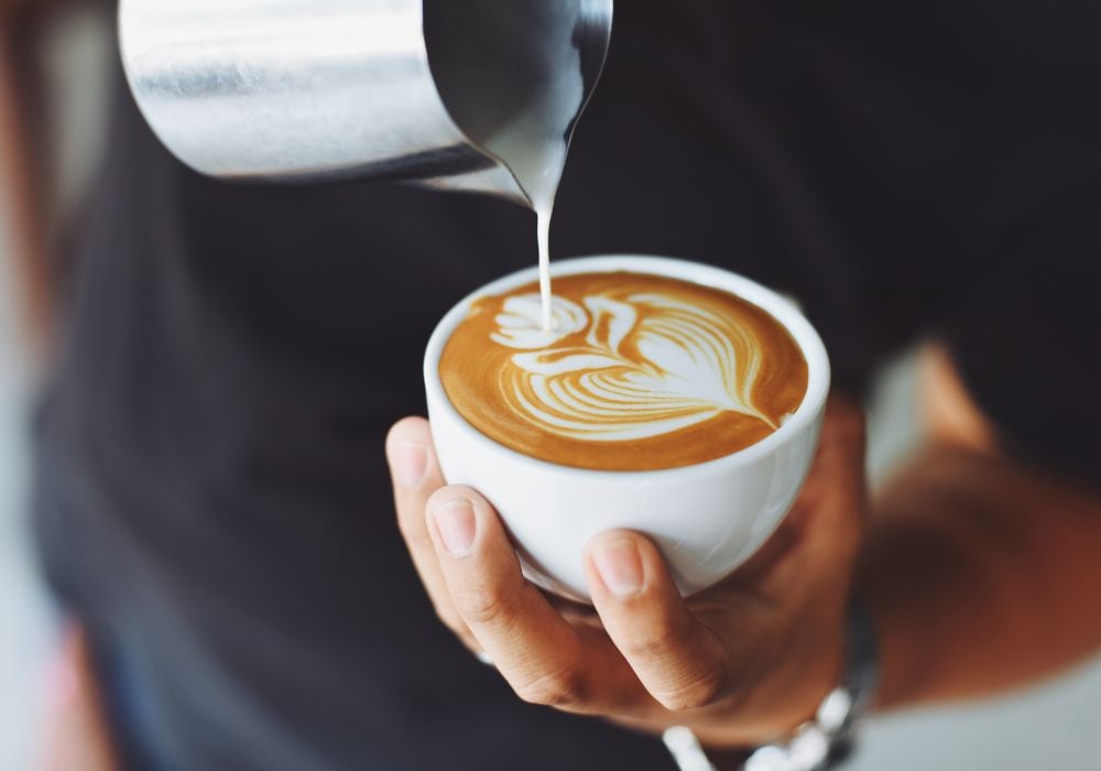 A barista performing coffee art for a cappuccino