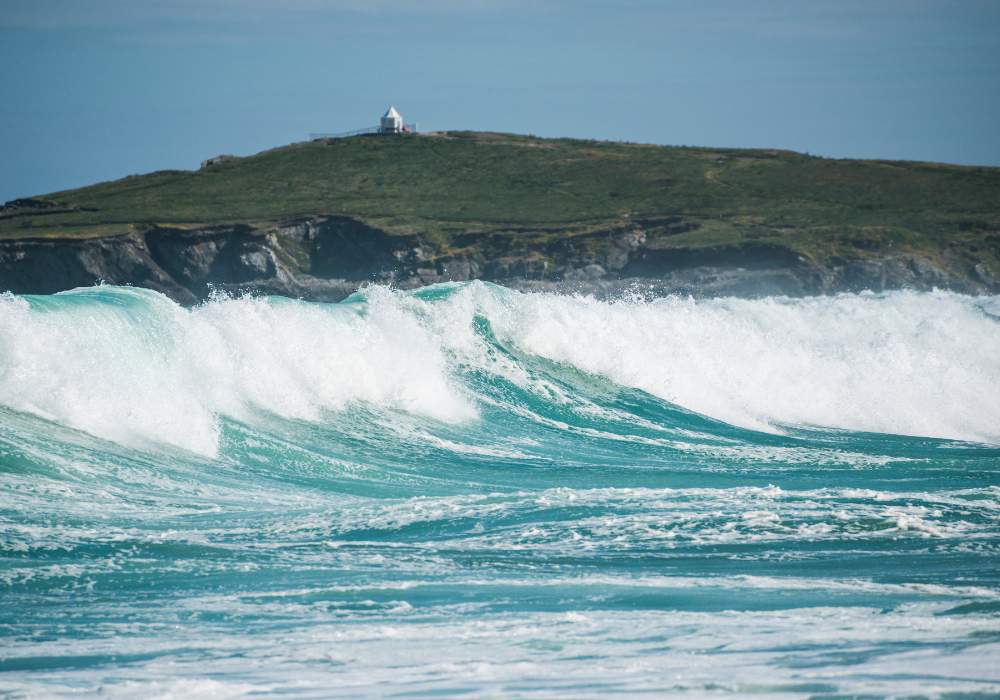 Waves comes rolling in at Cornwall's famous surf beach, Fistral beach with headland point visible in the distance.