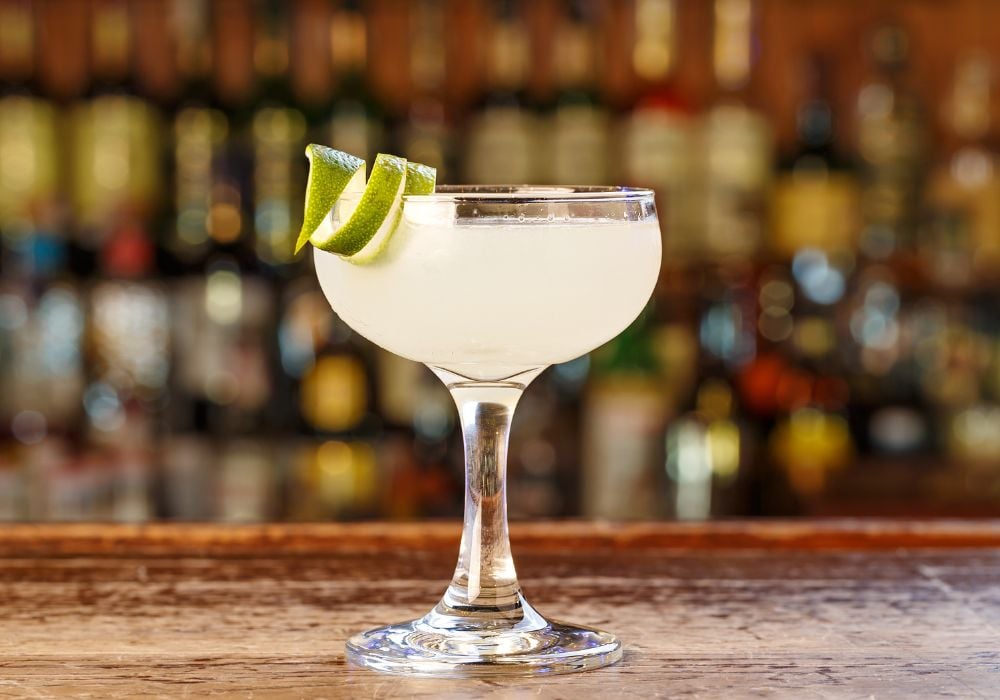 A traditional cocktail, a frozen daiquiri, is on the wooden counter.