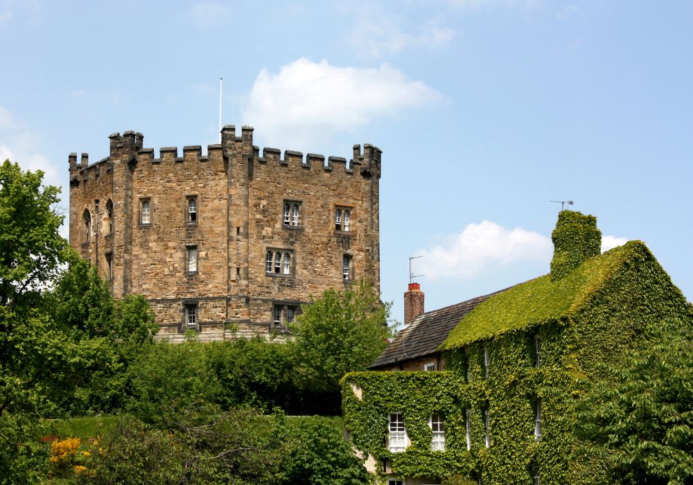 A stunning view of Durham Castle in England with clouds and blue sky behind it