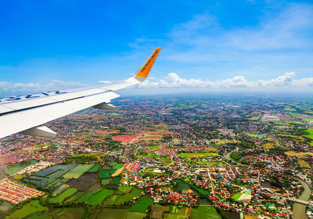 The wing of a Cebu Pacific plane flying above the Manila suburbs in the Philippines.