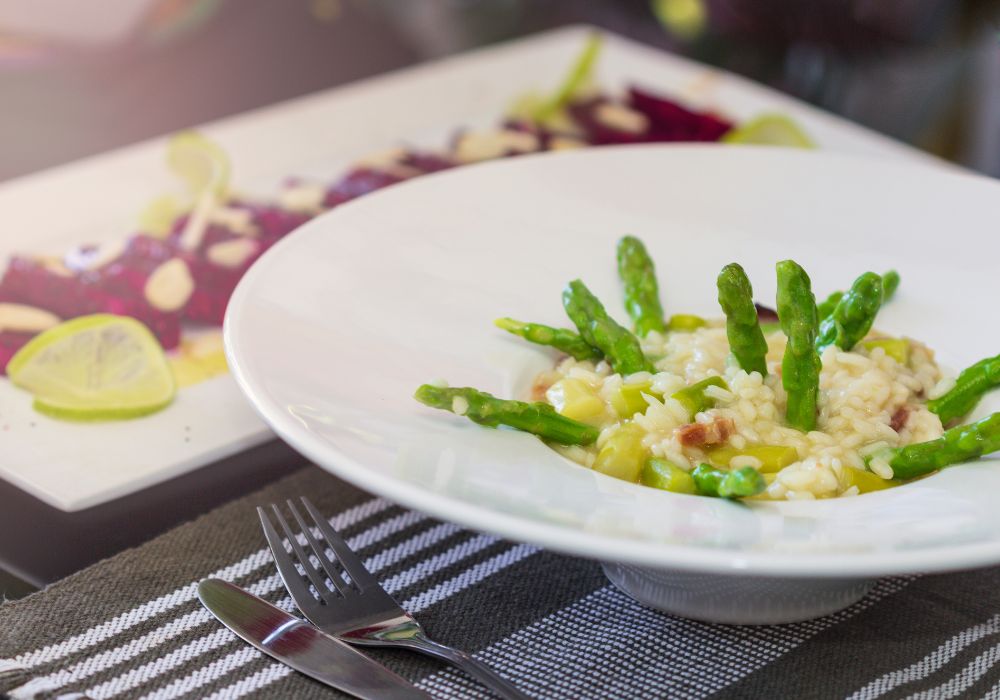 Asparagus risotto served on white plate.