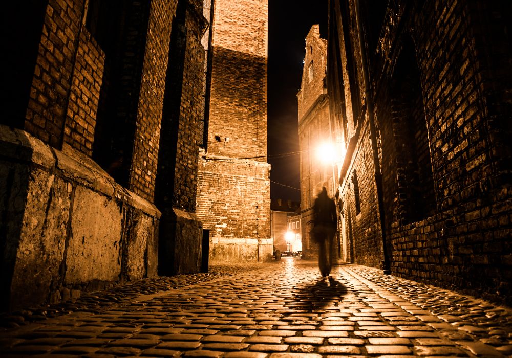 Illuminated cobbled street with light reflections on cobblestones in old historical city by night.