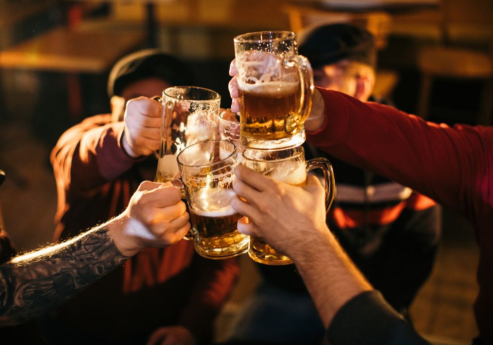 A group of men, sitting in a pub all together, holding beer mugs up