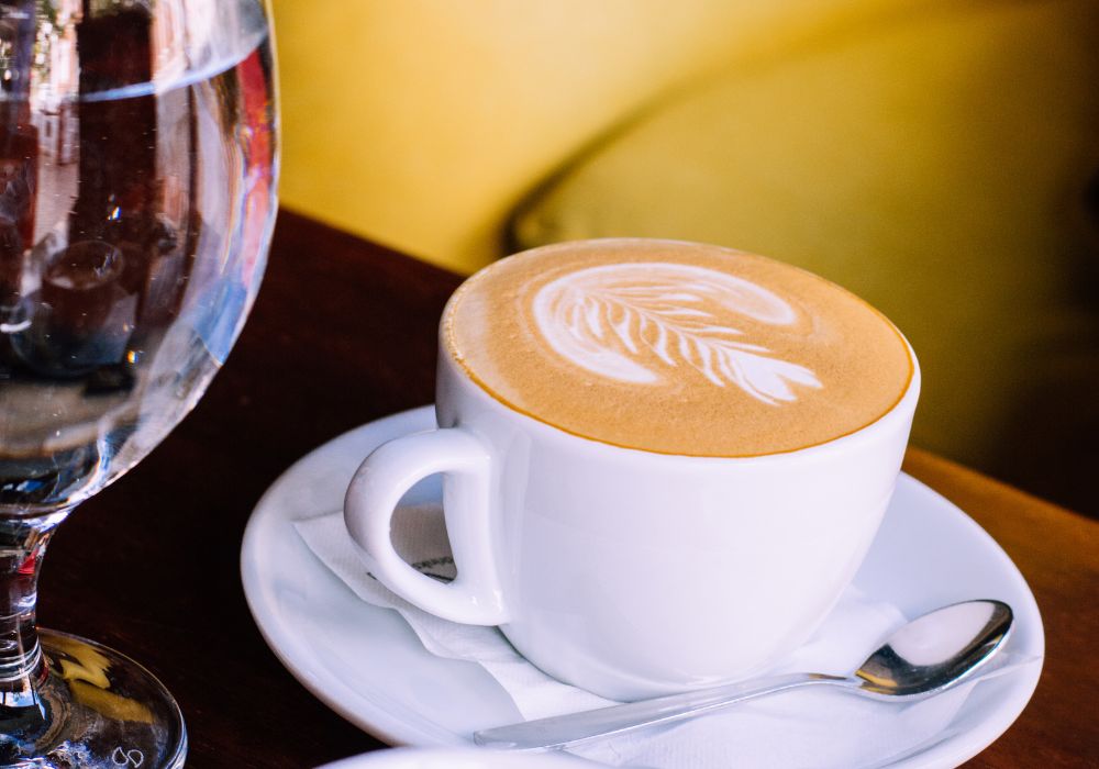 Froth art in a cup of espresso coffee with milk on a white ceramic plate on a table