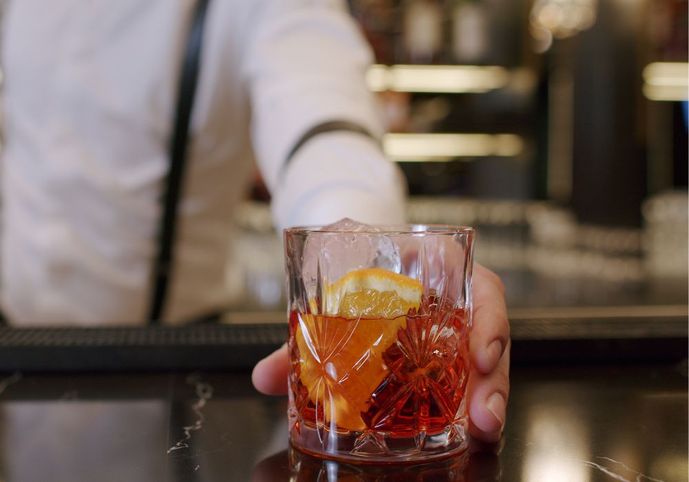 Close-up of a professional bartender mixing an alcoholic cocktail with long-lasting crystal ice cubes for a customer