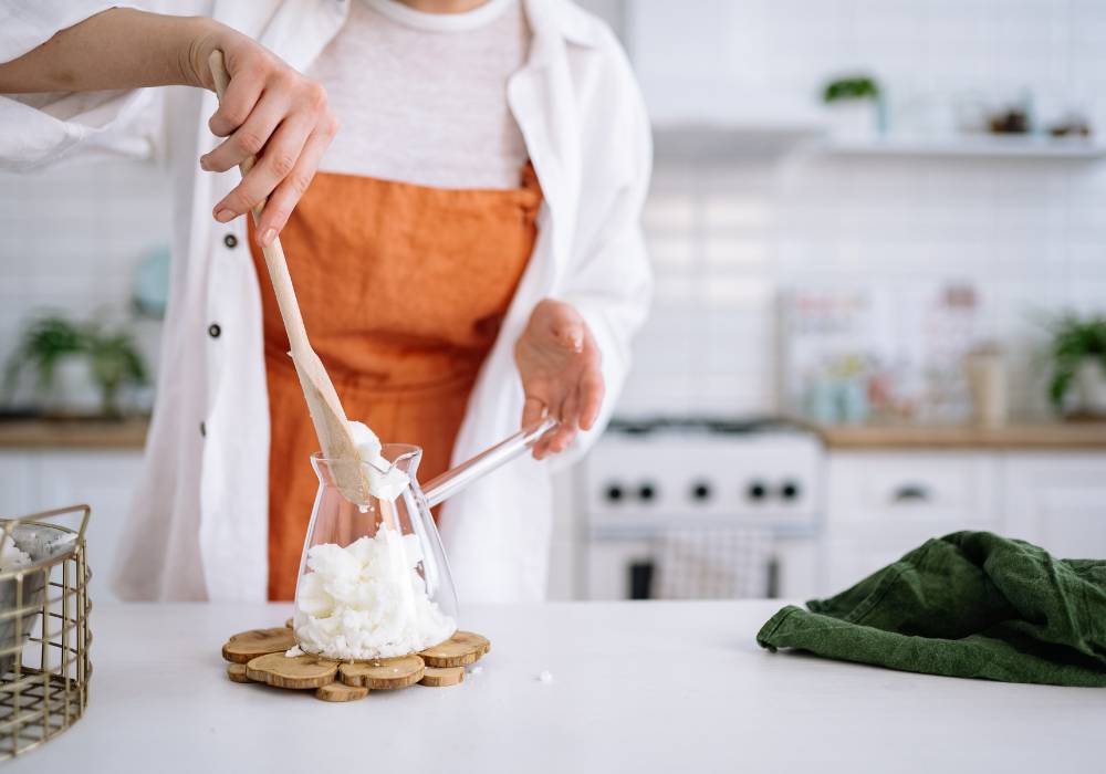 A woman in a lab coat makes candles in her kitchen for her candle making niche site