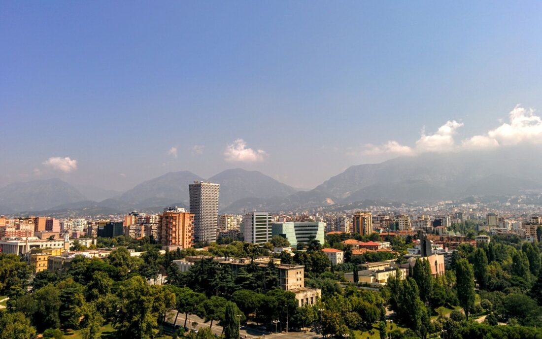 A view of a grey concrete building in the middle of the city under a blue sky