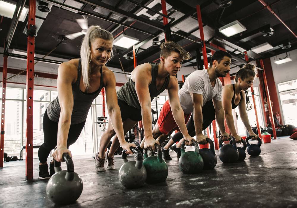 Men and women workout in the gym with kettlebells side-by-side