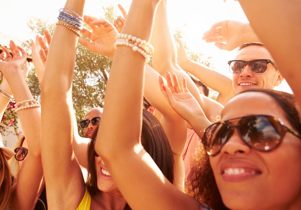 friends dancing with arms in the air at an outdoor concert