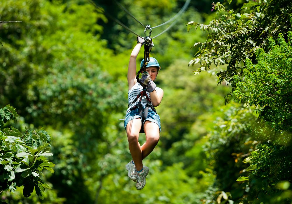 woman ziplining through the trees