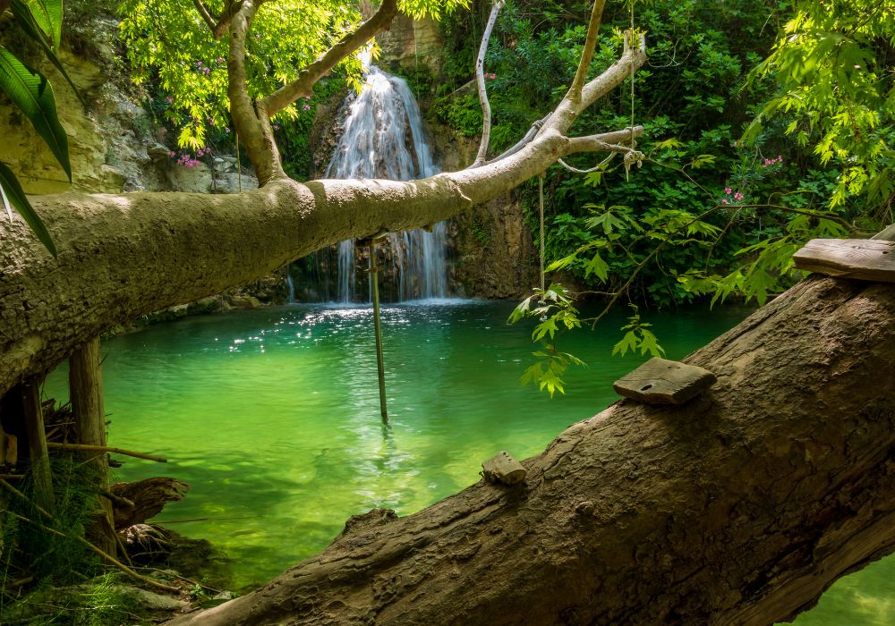 adonis baths in cyprus with green, clear water, a waterfall and green trees