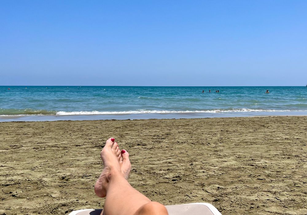 relaxing at mackenzie beach in larnaca with sand a woman's feet and the sea