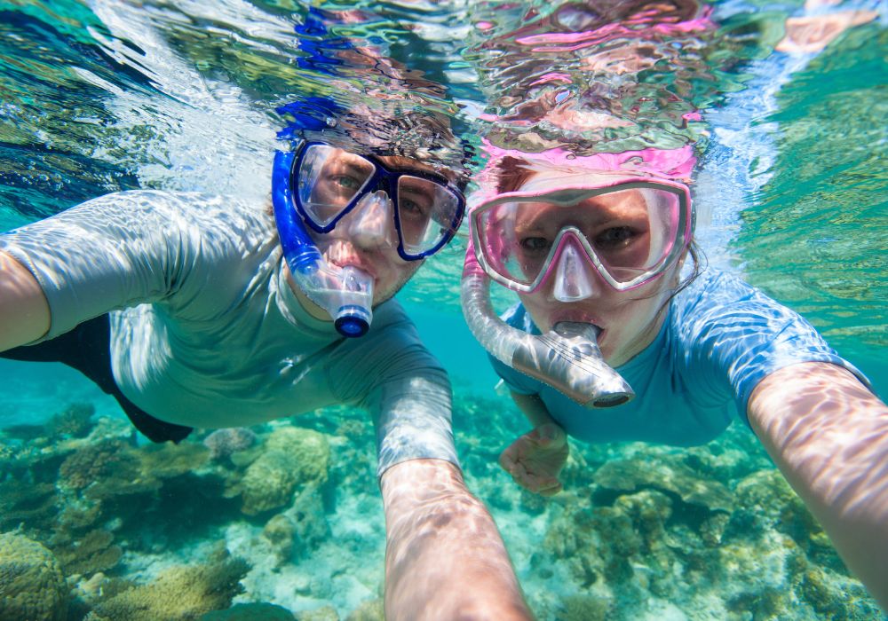 "An underwater photo captures a couple snorkeling in the ocean.