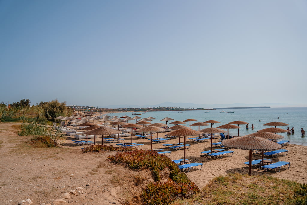 Chrissi Akti beach in paros greece. grass thatched umbrellas and beach beds with blue sea