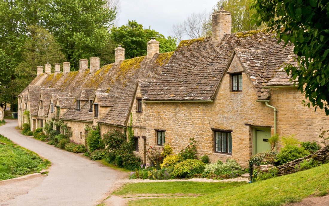 A little, tiny, ancient village with a grey stone roof, brown brick walls, and trees.