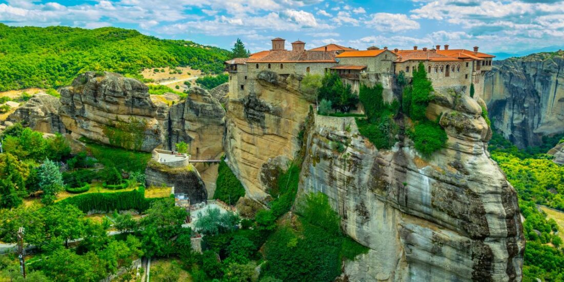 varlaam monastery with a red roof sitting on the edge of a rocky outcrop in greece