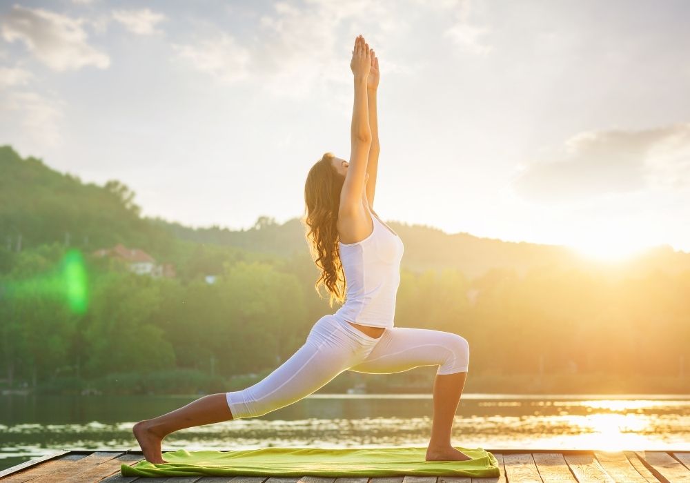 Woman doing yoga next to water