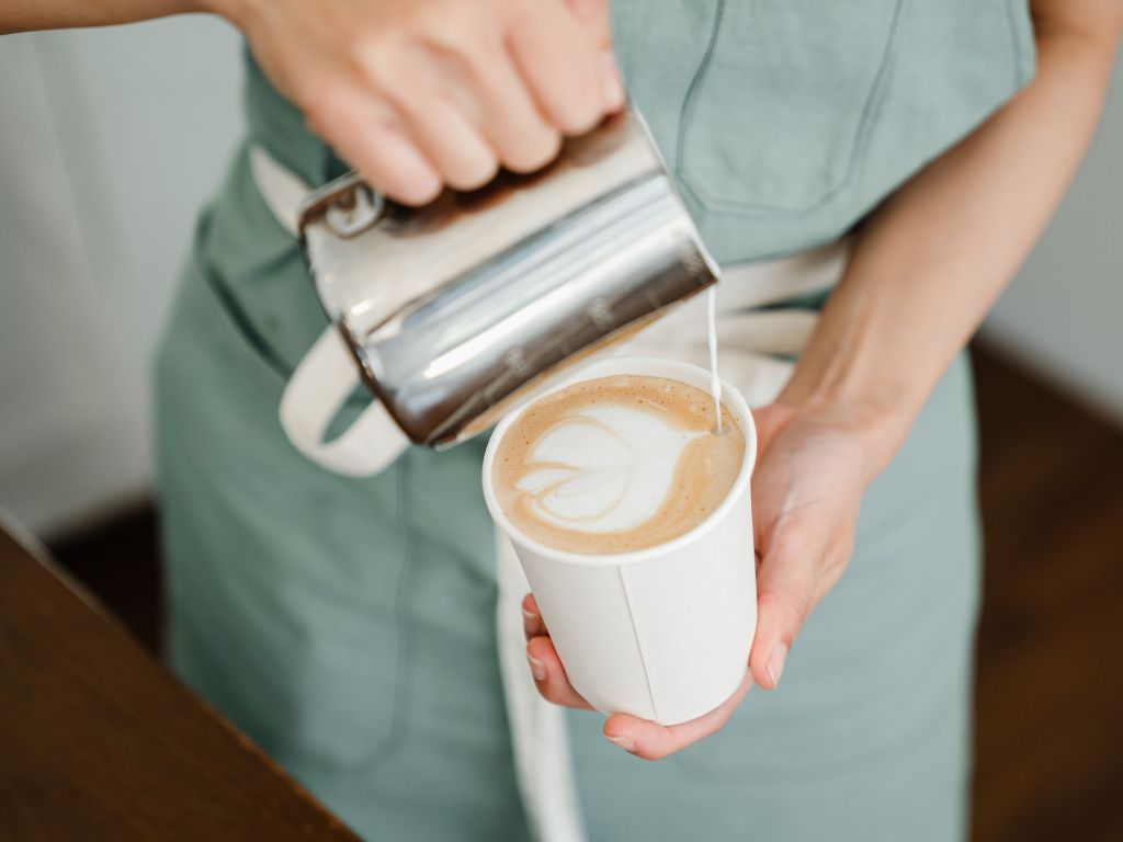 barista pouring milk into a lattee