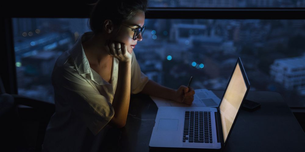 Woman working on her laptop at night