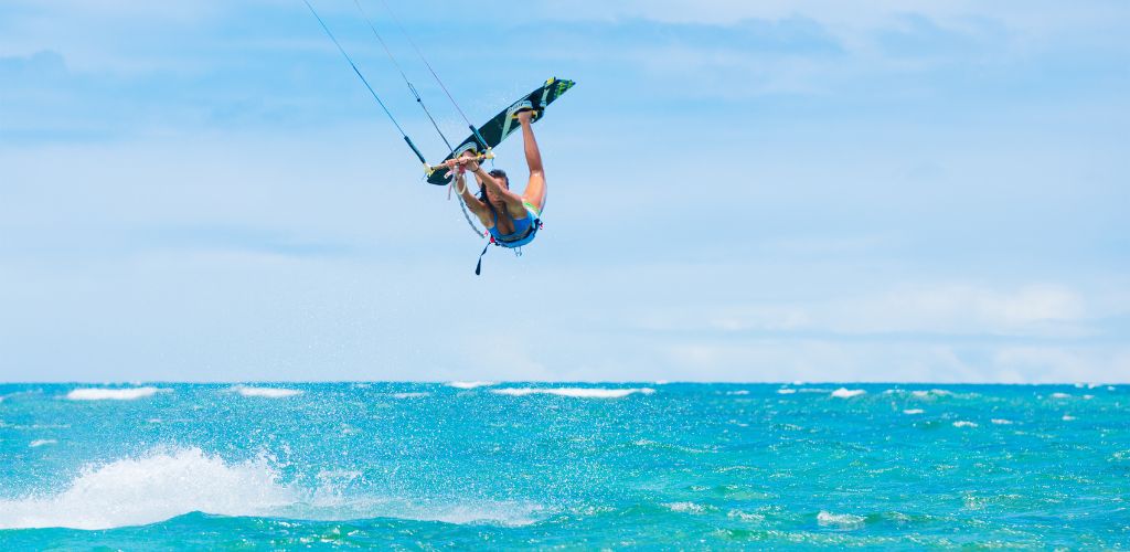 A woman kite surfing and getting huge air over the caribbean sea in Tulum